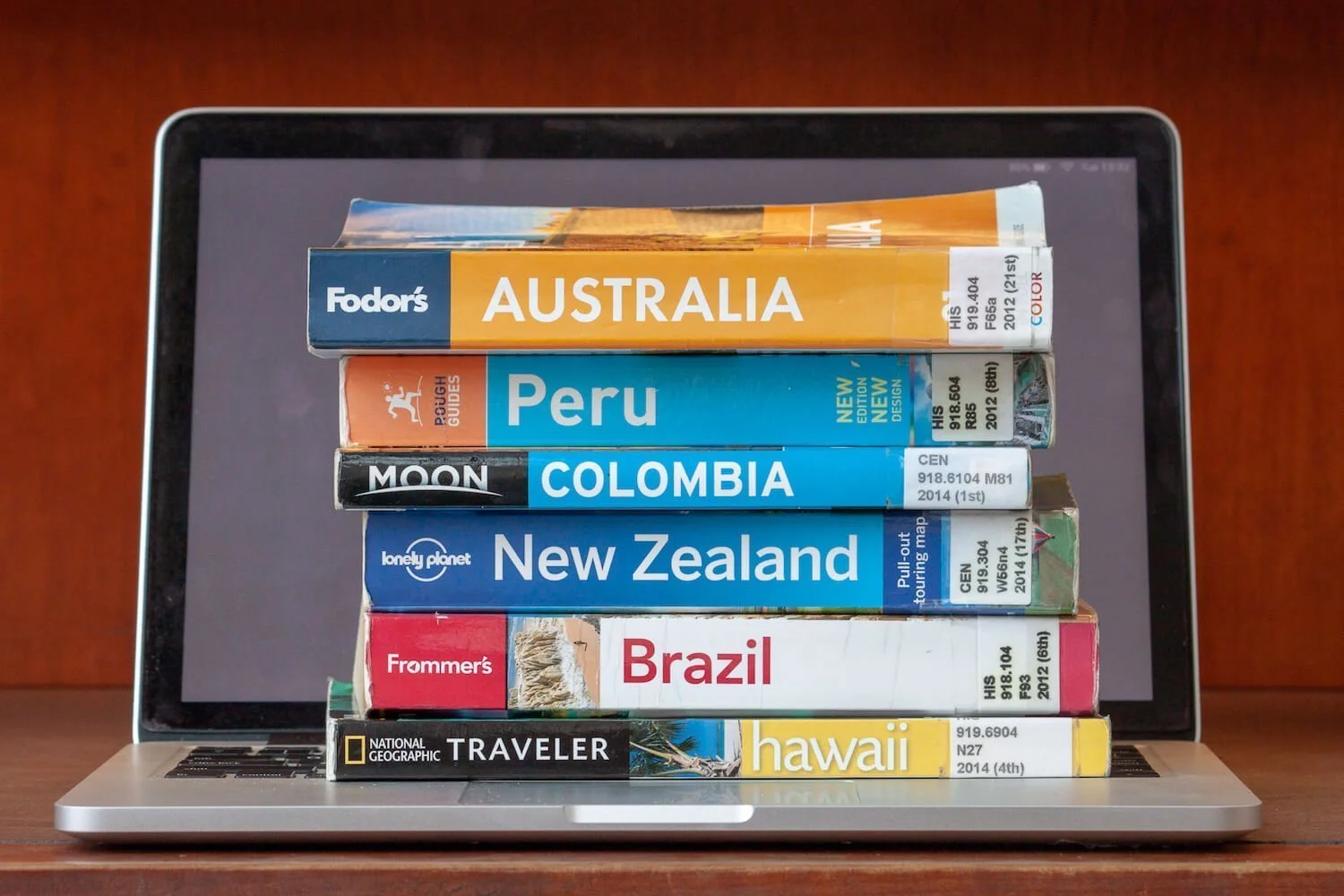 Travel guidebooks vs blogs cover image of travel guides stacked on top of a laptop